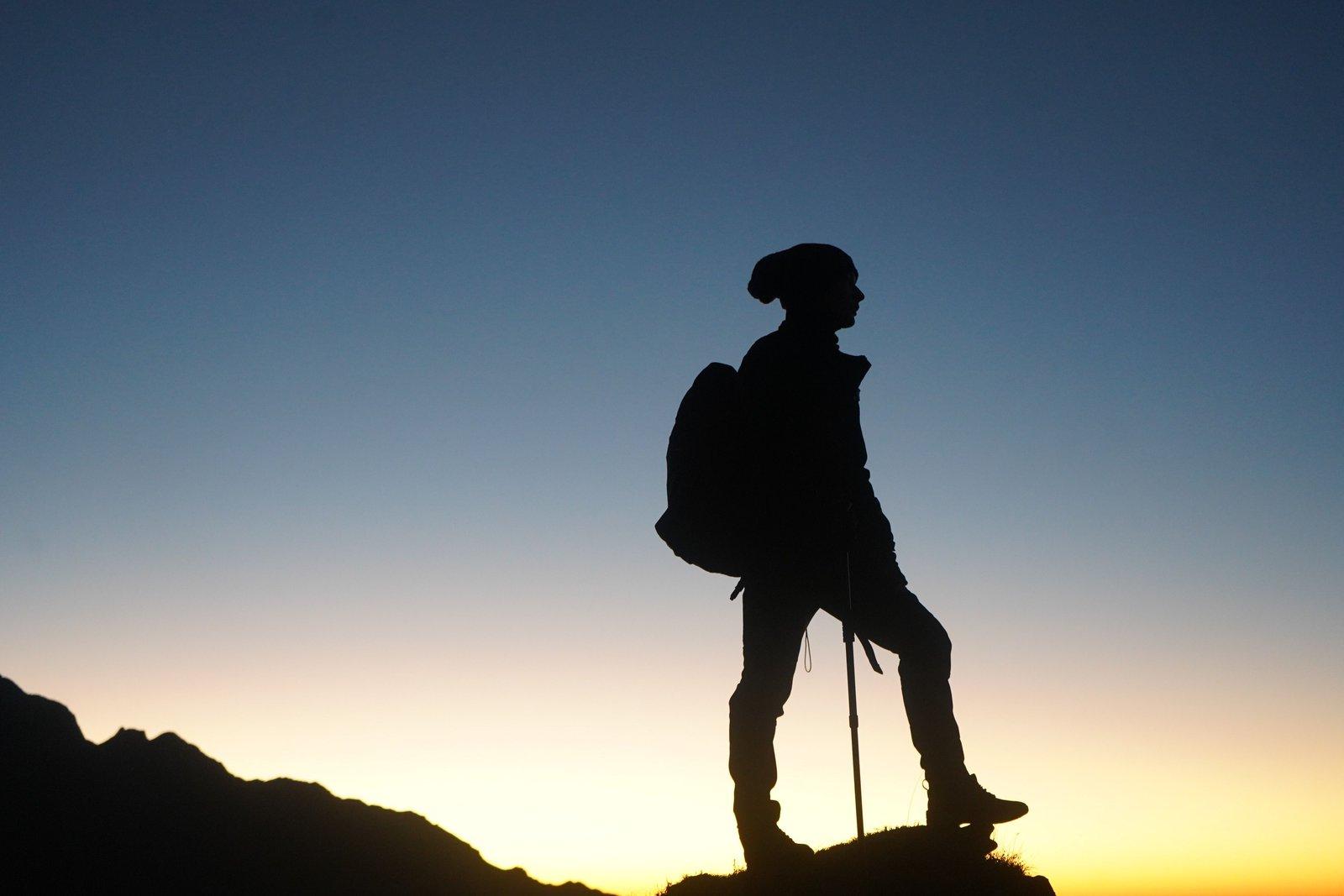 Hiker standing on a mountain ridge at sunset